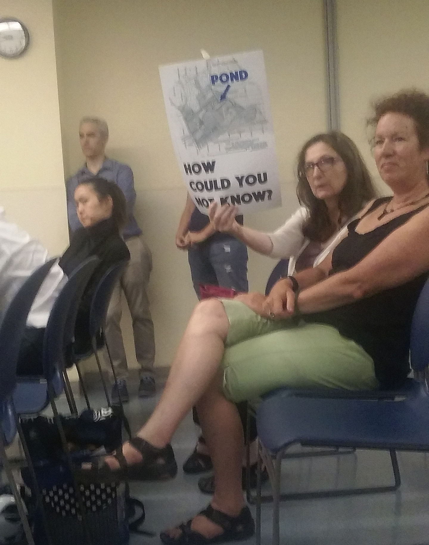 Residents at July Community Board # 3 land use committee meeting holding up signs asserting knowlingly buying a property with potential conditions is a self-imposed burden.
