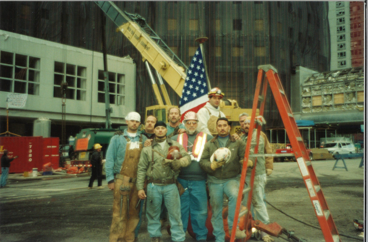 9 Unknown Workers Pose for a Photo With the Flag