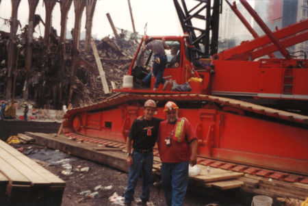 Two Unknown Workers Take a Photo infront of two men working on a Crane