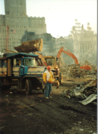 Worker Standing infront of a Truck and Digger at Ground Zero with 140 West St in the Back