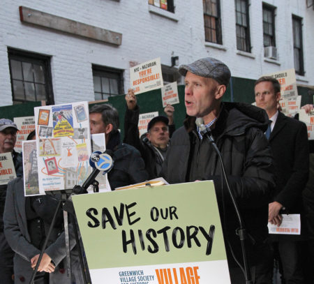 Andrew Berman at microphone, crowd behind holding signs demanding change in landmarks oversight